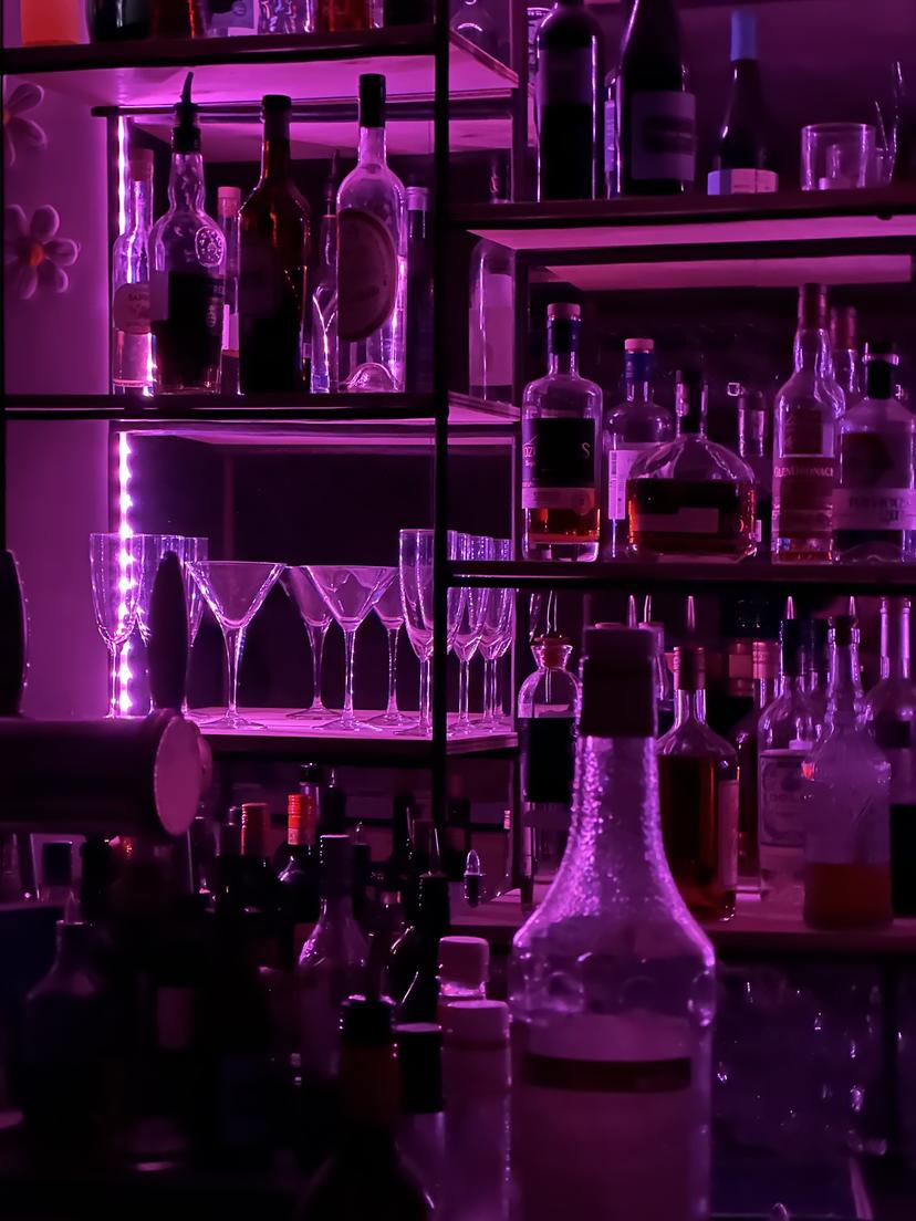 Quelques bouteilles du bar sur un fond de néons rose.